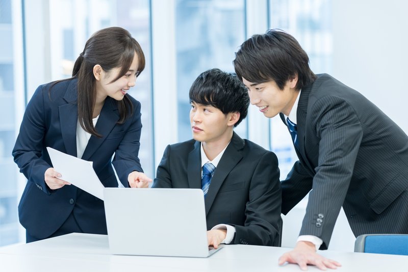 オフィスで3人のビジネスパーソンがノートPCと書類を見ながら資金調達の選択肢を比較検討している様子