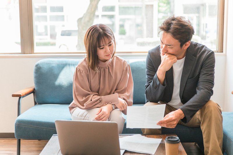 書類を見ながら融資の返済計画について考え込む男女のビジネスパーソン